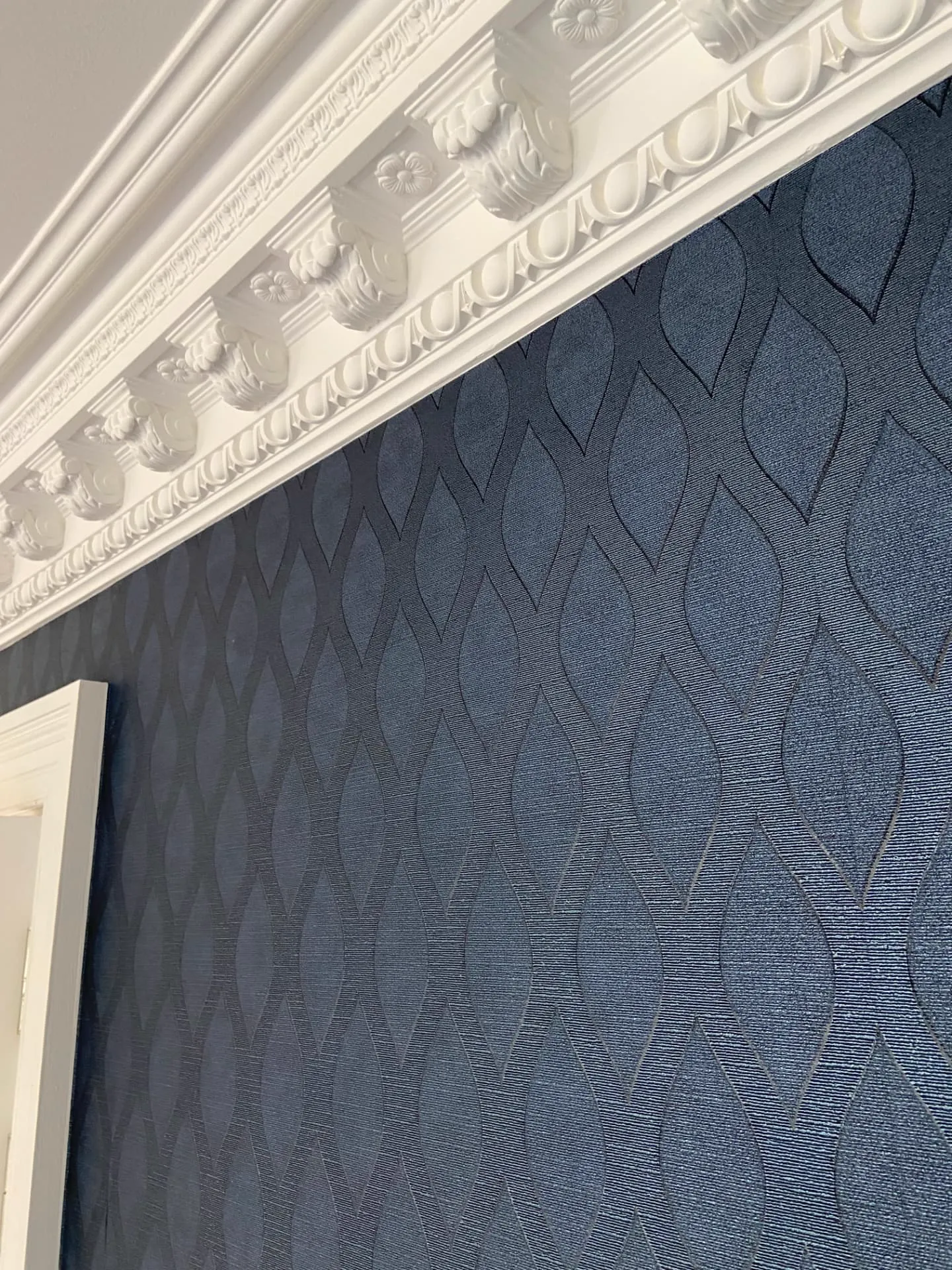 Navy textured wallpaper beneath an ornate white cornice and architrave in a period house, decorating in Belgravia by coreMaint